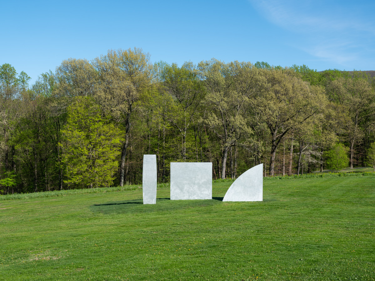 Three aluminum sculptures by Ellsworth Kelly installed on Storm King's east hillside, each a different shape: column, square, and a triangle wtih one curved edge.
